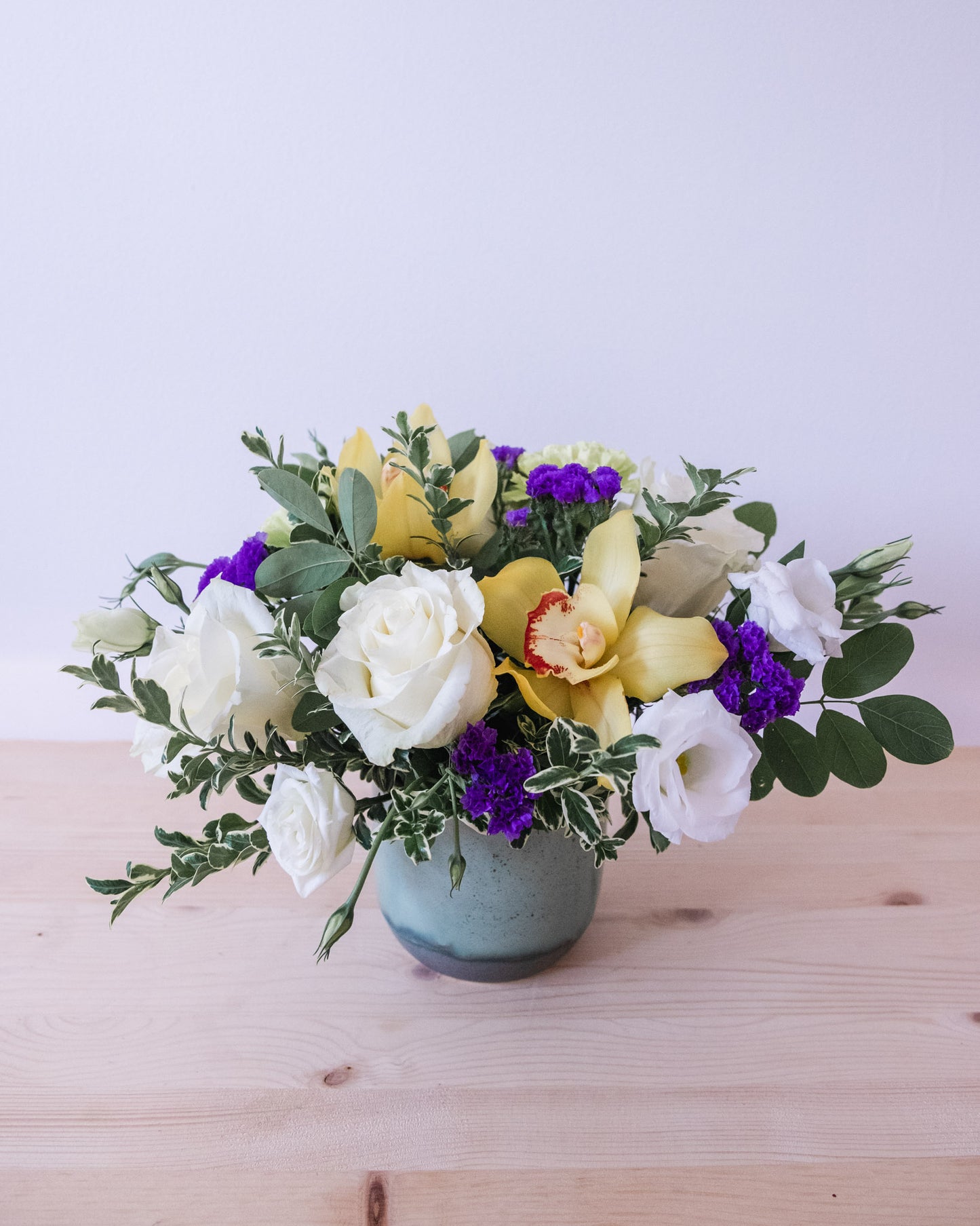 Yellow orchids, White roses, purple status, mixed greenery