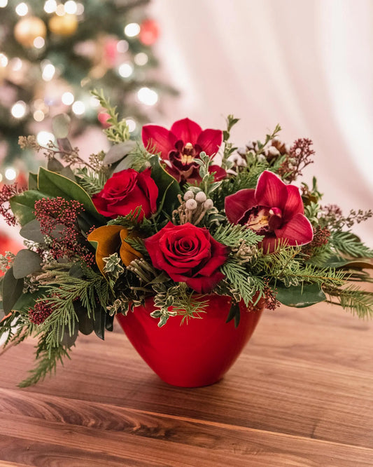 burgundy orchids, red roses, berries, evergreens, ceramic container, center piece