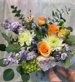 A fresh cut bouquet featuring a variety of flowers including stock, peony, and other blooms in pastel colors.