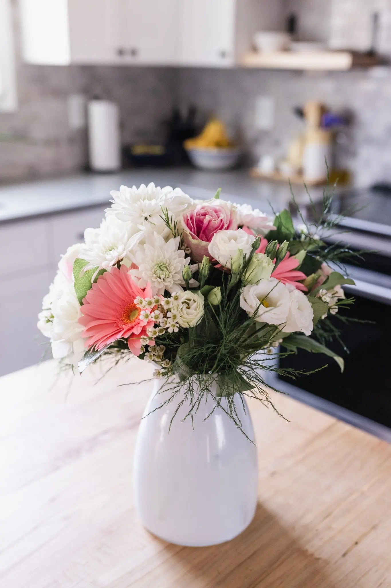 A contemporary white vase containing a beautiful arrangement of pink and white flowers, for the home